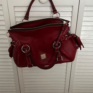 Red leather Dooney and Bourke handbag with tassel accents and braided handles.